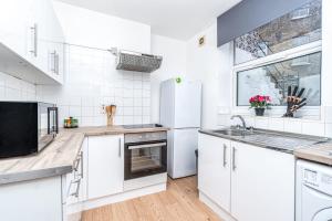 a white kitchen with a sink and a refrigerator at Lovely 2 Bedroom in Lower Clapton in London