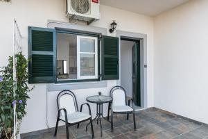eine Terrasse mit 2 Stühlen, einem Tisch und einem Fenster in der Unterkunft Angelos Seaview Studios by Konnect, Kommeno Corfu in Kommeno