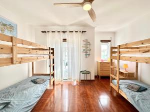 two bunk beds in a room with a ceiling fan at Baleal Happiness Surf House in Ferrel