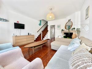 a living room with a couch and a tv at Baleal Happiness Surf House in Ferrel