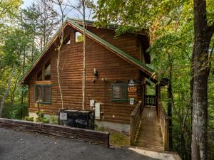 a log cabin in the woods with a porch and stairs at Bear Necessities, 1 Bedroom, Sleeps 8, Pool Table, Arcade, WiFi, Pets in Gatlinburg