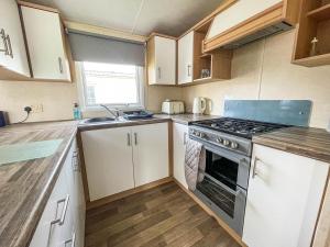 a kitchen with white cabinets and a stove top oven at Lovely 8 Berth Caravan At Southview Holiday Park Near Skegness Beach Ref 33031cl in Skegness