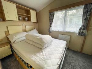 a bedroom with a large white bed with a window at Lovely 8 Berth Caravan At Southview Holiday Park Near Skegness Beach Ref 33031cl in Skegness
