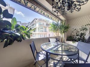 uma varanda com uma mesa de vidro, cadeiras e plantas em Nestor&Jeeves - FLEURS TERRASSE - 3 chambres em Nice