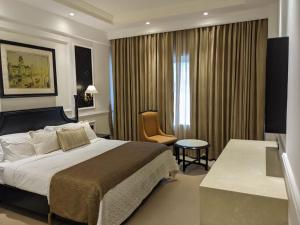um quarto de hotel com uma cama e uma cadeira em Peerless Hotel Kolkata em Calcutá