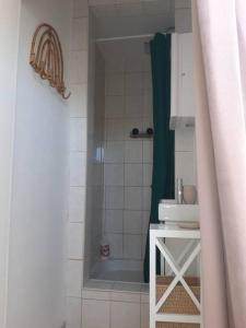 La salle de bains blanche est pourvue d'une douche et d'un lavabo blanc. dans l'établissement Au chovelète, à Rochefort