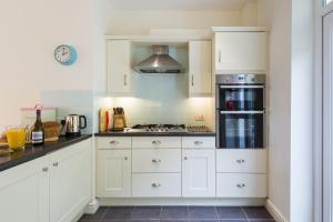 a kitchen with white cabinets and a stove top oven at Bryn Gwyn & Tegfryn a Pair of Cottages Sea & Mountain Views Borth y Gest in Porthmadog
