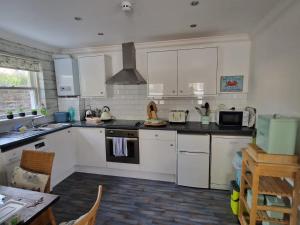 cocina con armarios blancos y fogones en The Beach House en Eastbourne