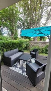 een patio met een tafel en stoelen en een blauwe parasol bij Plein cœur de Carteret in Barneville-Carteret