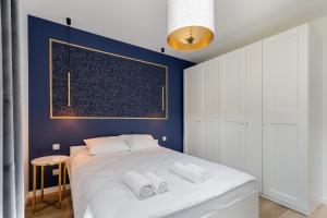 een slaapkamer met een wit bed en een blauwe muur bij Park Krowoderski Comfort Apartment in Krakau