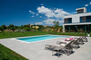 a swimming pool with lounge chairs and a house at Villa Arestea in Vodnjan