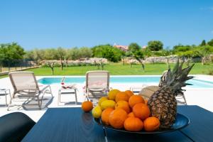 a plate of fruit on a table next to a pool at Villa Arestea in Vodnjan