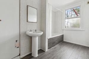 Baño blanco con lavabo y espejo en Cozy London Flat, en Londres