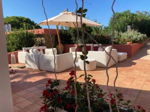 a patio with white couches and an umbrella at Cala Rosa Club Hotel in Stintino