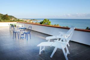 un patio con sillas, mesas y el océano en OASI SICILIANA, en Caronia