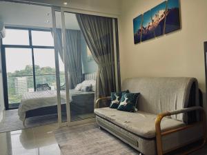a bedroom with a bed and a couch and a window at NOSTRE HOMESTAY THE SHORE KK in Kota Kinabalu