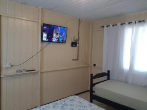 een slaapkamer met een tv aan de muur en een bed bij Pousada Max Boesing in São Francisco do Sul