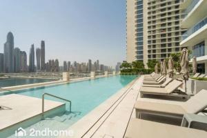 einen Pool mit Liegestühlen und eine Skyline der Stadt in der Unterkunft 2ndhome - Newly Furnished - Marina Vista in Dubai