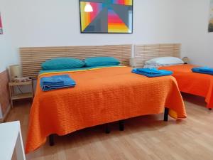 ターラントにあるB&B Ciccioのオレンジのシーツと青い枕が備わる客室のベッド2台