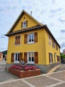 una casa amarilla con flores delante en Cosy Bretzel, en Gresswiller