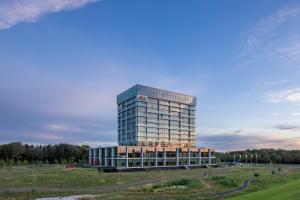 een hoog glazen gebouw in het midden van een veld bij Van der Valk Hotel Eindhoven-Best in Best
