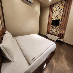 a bedroom with a bed with white sheets and a window at The Mint Nanded Hotel in Nānded