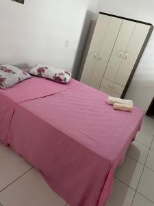 a bedroom with a pink bed with two towels on it at Reis Veloso in Parnaíba