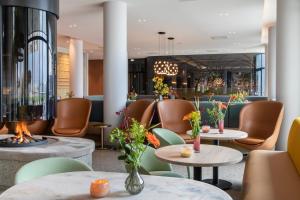 een restaurant met tafels en stoelen en een open haard bij Van der Valk Hotel Deventer in Deventer