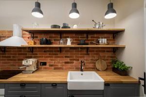cocina con fregadero y pared de ladrillo en Nobel Apartment - BEST LOCATION!, en Cracovia 7 fotos más