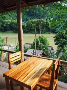 Meexok river view في Nongkhiaw: طاولة وكراسي خشبية على شرفة مطلة
