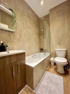 a bathroom with a toilet and a tub and a sink at Islington - Greater London Apartment in London