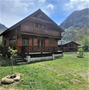 a large wooden house in a field of grass at Chalet chaleureux à Orlu avec Jacuzzi et vue sur la montagne in Orlu