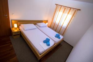 a bedroom with a bed with two blue pillows and a window at Apartments Kelić in Trogir