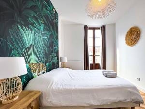 a bedroom with a large bed with a tropical wallpaper at Hyper-centre de Grenoble, ambiance tropicale, wifi fibre in Grenoble