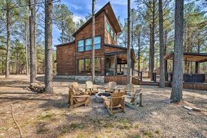 una cabaña de madera con sillas y una hoguera en el bosque en Family Getaway 10-Bed Cabin w Hot tub & Firepit, en Broken Bow