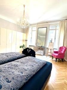a bedroom with a large bed and a pink chair at Stephansdom apartment in Vienna