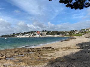 a sandy beach with houses in the background and the ocean at Fresh, bright house, fab views, 6 mins to the sea, onsite parking x 2 in Saint Mawes