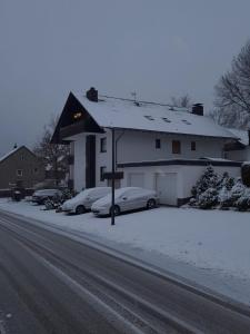 a house with two cars parked in the snow at Haus Annemiek in Winterberg