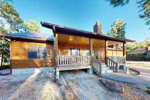 Cabaña de madera con porche y 2 bancos en Osprey Cabin, en Pinetop-Lakeside