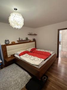 een slaapkamer met een bed met rode kussens en een kroonluchter bij Villa Ossiacher Tauern in Feldkirchen in Kärnten