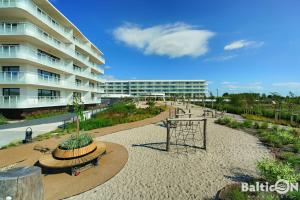 un gran edificio de apartamentos con un parque infantil delante de él en Apartamenty BalticON Polanki Aqua en Kołobrzeg