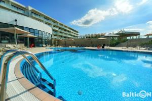 a large blue swimming pool in front of a building at Apartamenty BalticON Polanki Aqua in Kołobrzeg +37 photos