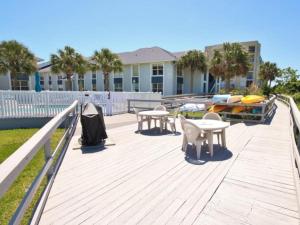 a deck with tables and chairs and a boat at Kiawah Bay 106 in New Smyrna Beach
