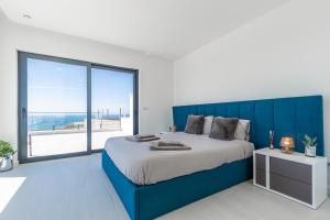 a bedroom with a blue bed and a large window at Villa Locki with jacuzzi, private pool and sea view in Lourinhã