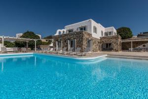 a villa with a swimming pool in front of a house at Astounding Mykonos Villa 6 Bedrooms Villa El Greco Panoramic Sea Views Facing the Ancient Island of Delos Aleomandra in Dexamenes