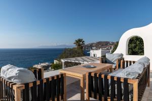 DexamenesにあるAstounding Mykonos Villa 6 Bedrooms Villa El Greco Panoramic Sea Views Facing the Ancient Island of Delos Aleomandraの木製テーブルと椅子、海を望むバルコニー