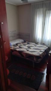 a small bedroom with a bed with a checkered blanket at Peñazcal casita feliz in Bilbao