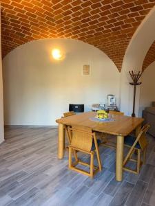 una mesa de madera y sillas en una habitación con una pared de ladrillo en Al Canun di Casale Monferrato, en Casale Monferrato