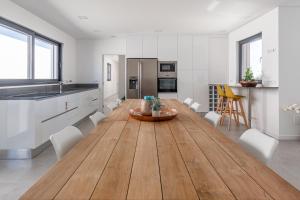洛里尼揚的住宿－Villa Locki，厨房配有长木桌和白色橱柜。