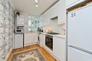 a white kitchen with white appliances and a rug at Botanical bliss near Kew Gardens by UnderTheDoormat in London